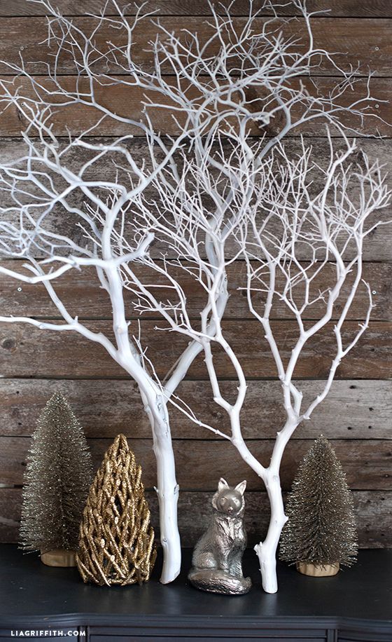 some white branches are sitting on top of a black mantle with other decorations and trees