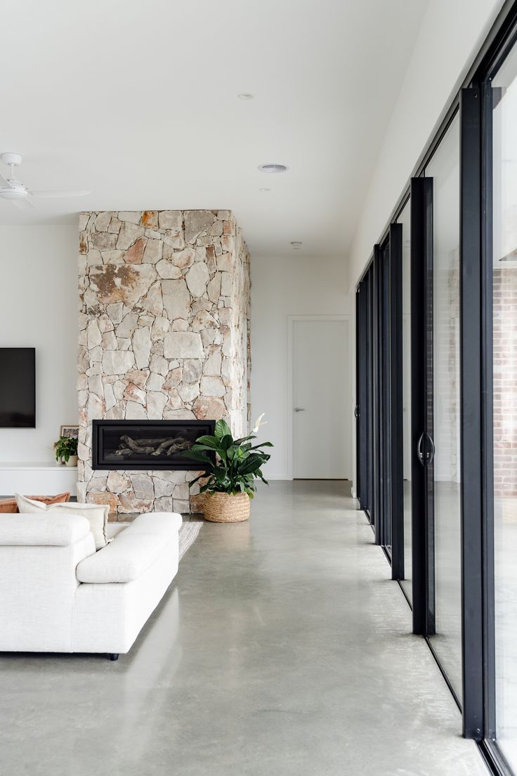 a living room with white couches and a stone fireplace in the middle of it