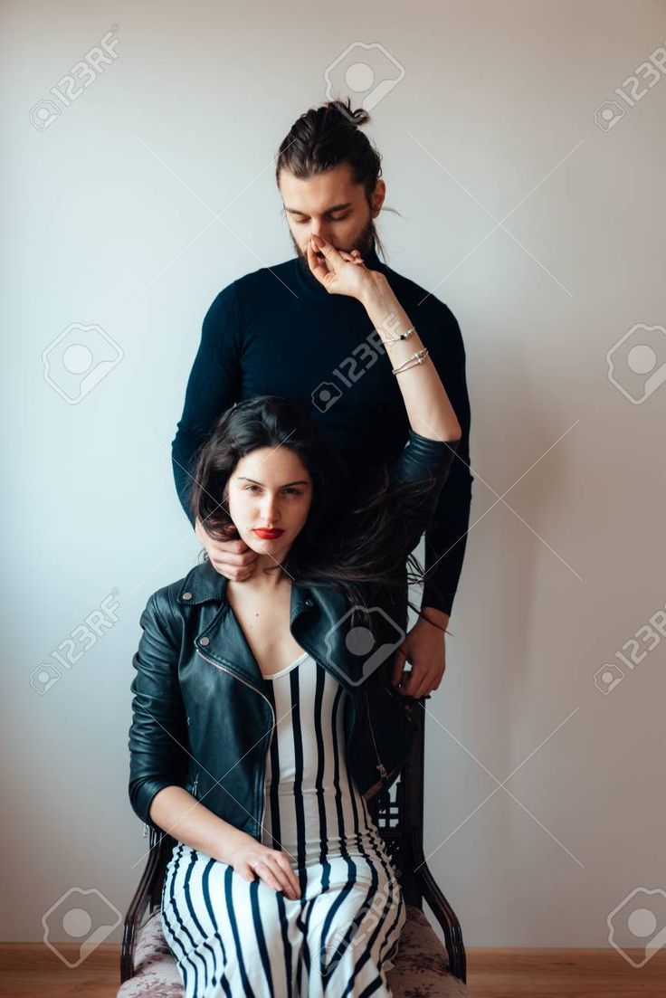 a woman sitting on top of a man's lap while he combs his hair