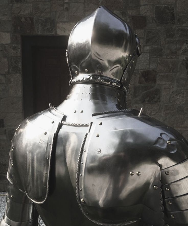 the back of a knight's armor on display in front of a stone building