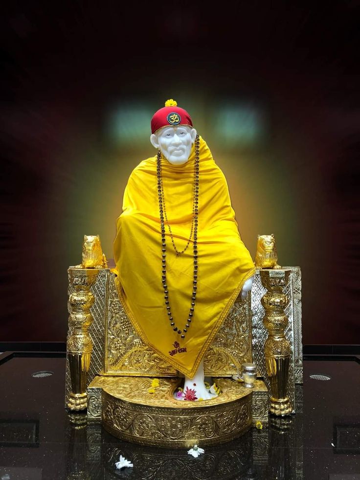 a statue of a man sitting on top of a golden chair with chains around his neck