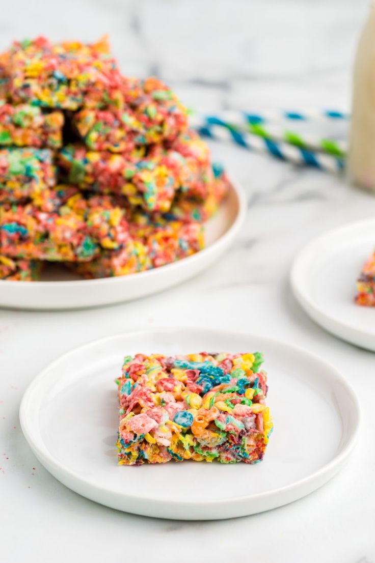 there are two white plates with colorful rice krispy treats on them