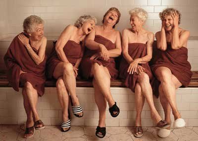 four older women sitting on a bench laughing