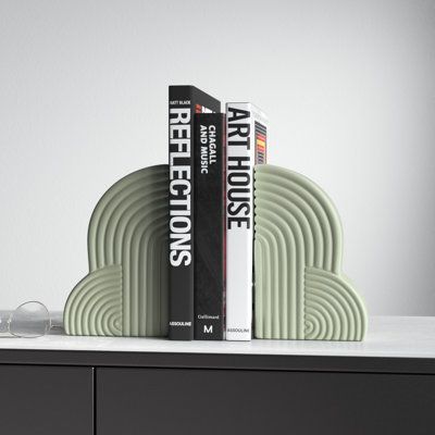 two books are sitting on top of a black cabinet next to some glass vases