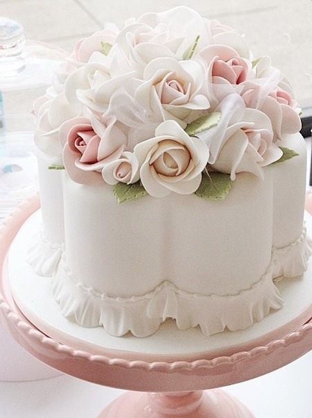 there is a white cake with pink flowers on the top and bottom, sitting on a plate