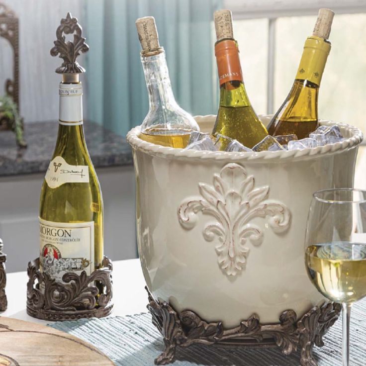 several bottles of wine in a bucket on a table with two glasses and a bottle opener