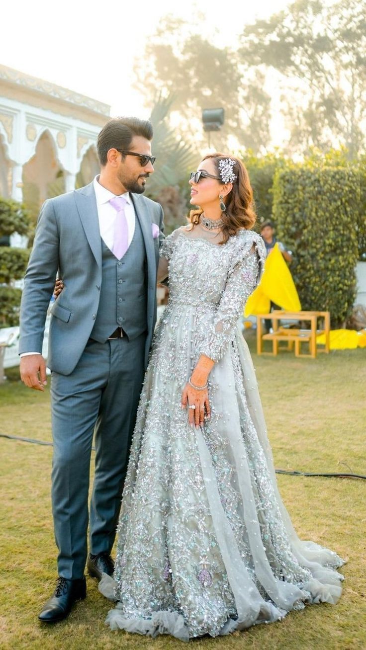 a man and woman standing next to each other in front of a building wearing formal attire