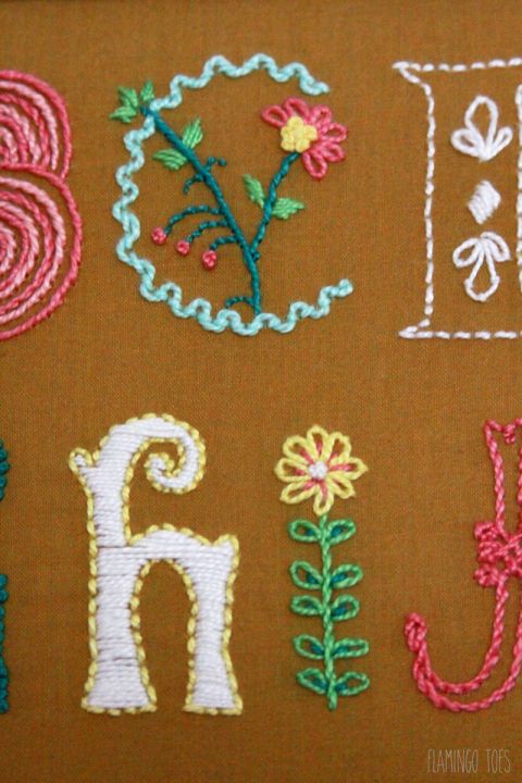 the letters are made up of different types of stitchs and thread, with flowers on them