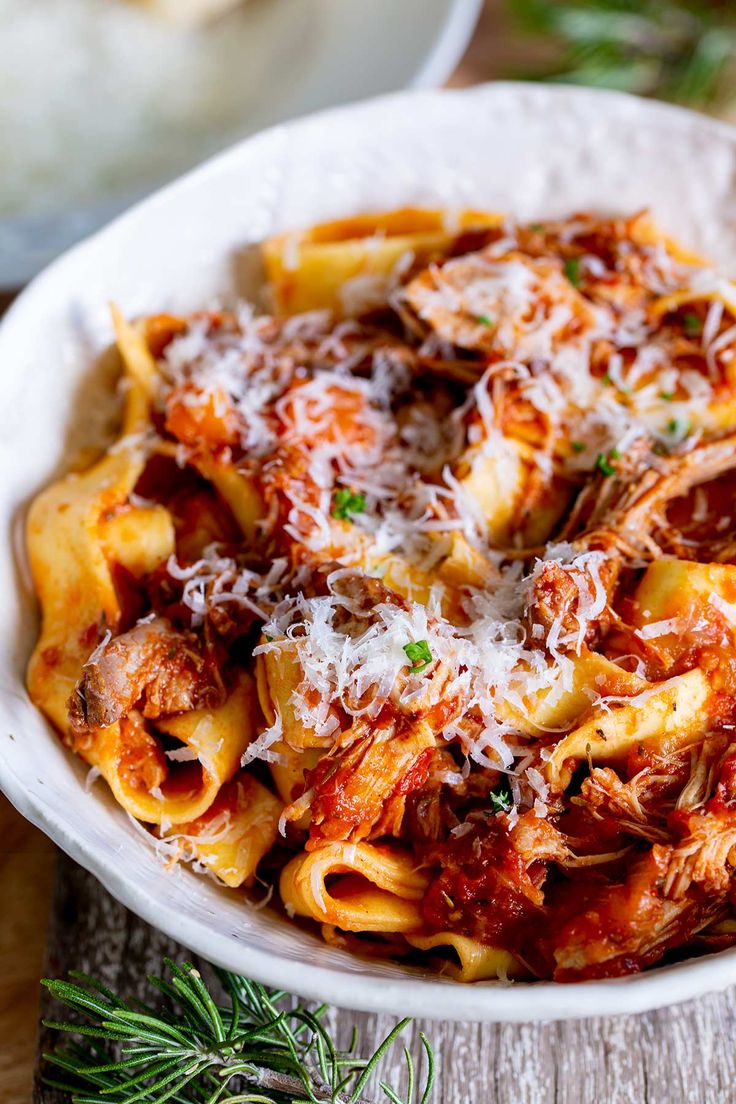 a white bowl filled with pasta covered in sauce and parmesan cheese on top