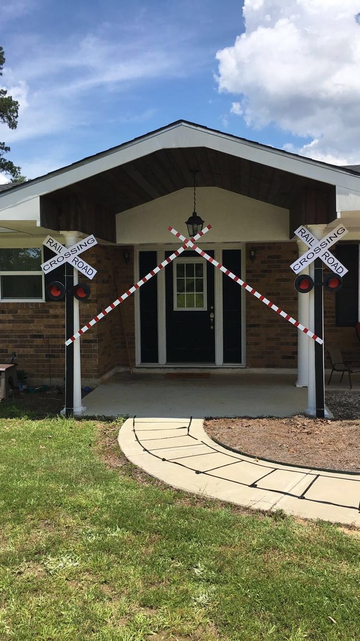 a house decorated for christmas with railroad crossing decorations on the front porch and side door