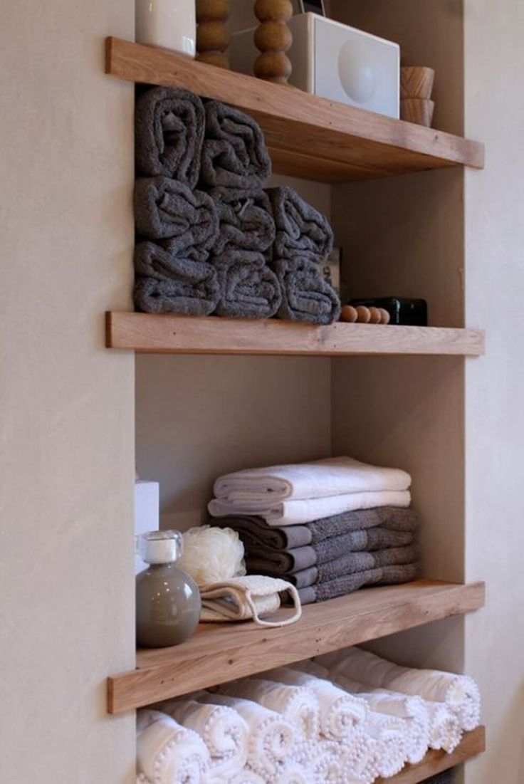 towels are stacked on wooden shelves in the bathroom