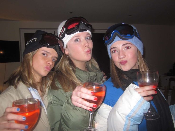 three women are holding wine glasses and posing for the camera while wearing ski goggles