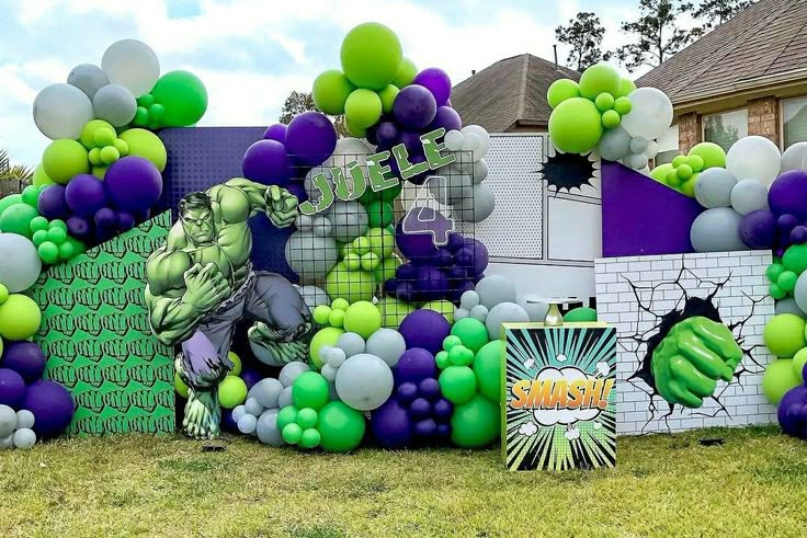 the balloon wall is decorated with green, purple and white balloons in front of a house