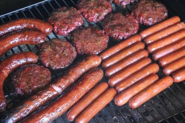 hot dogs and hamburgers are cooking on the grill