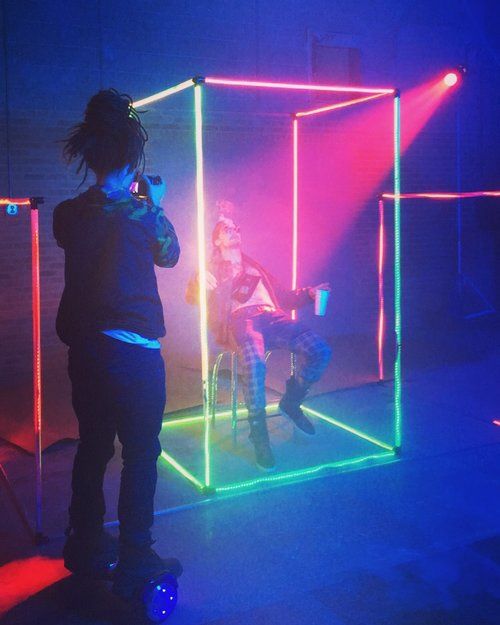 two people standing in front of a neon cube on stage with lights and sound equipment