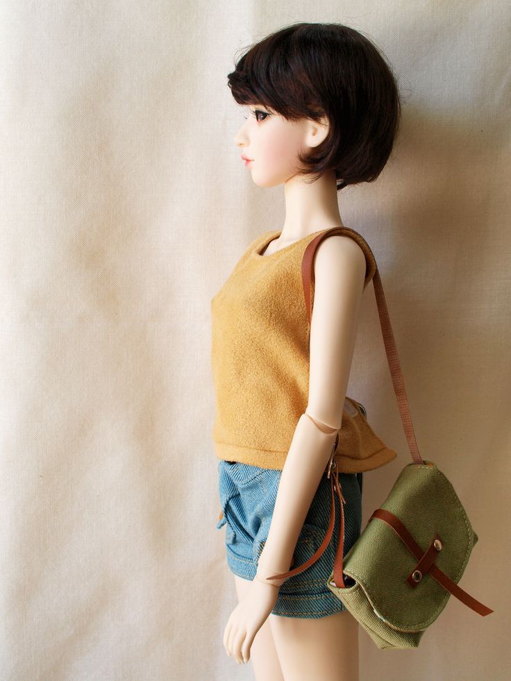 a mannequin holding a green purse on top of a white wall next to a brown bag