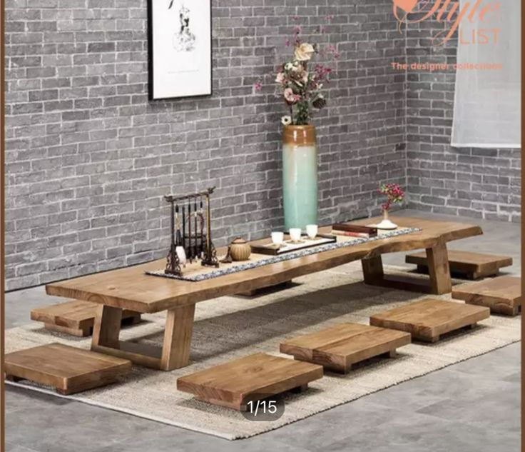 a wooden table with benches in front of a brick wall and vase filled with flowers