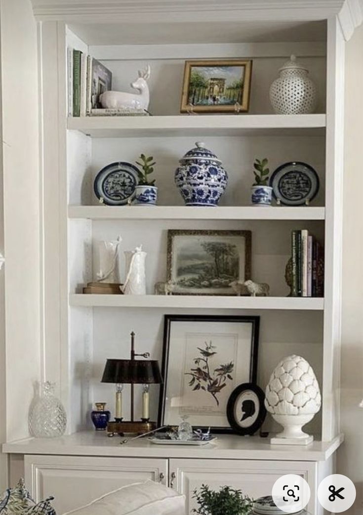 a white bookcase filled with lots of books and vases on top of it