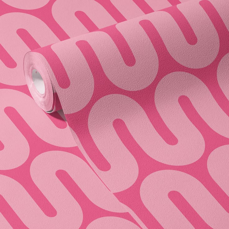 a roll of pink wallpaper with white circles on the side and one rolled up