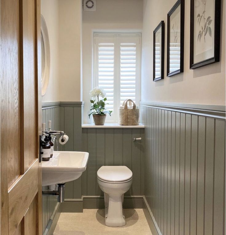 a white toilet sitting next to a sink in a bathroom under a window with shutters