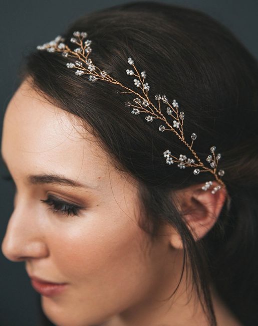 a woman wearing a bridal headpiece with flowers and leaves on it's side