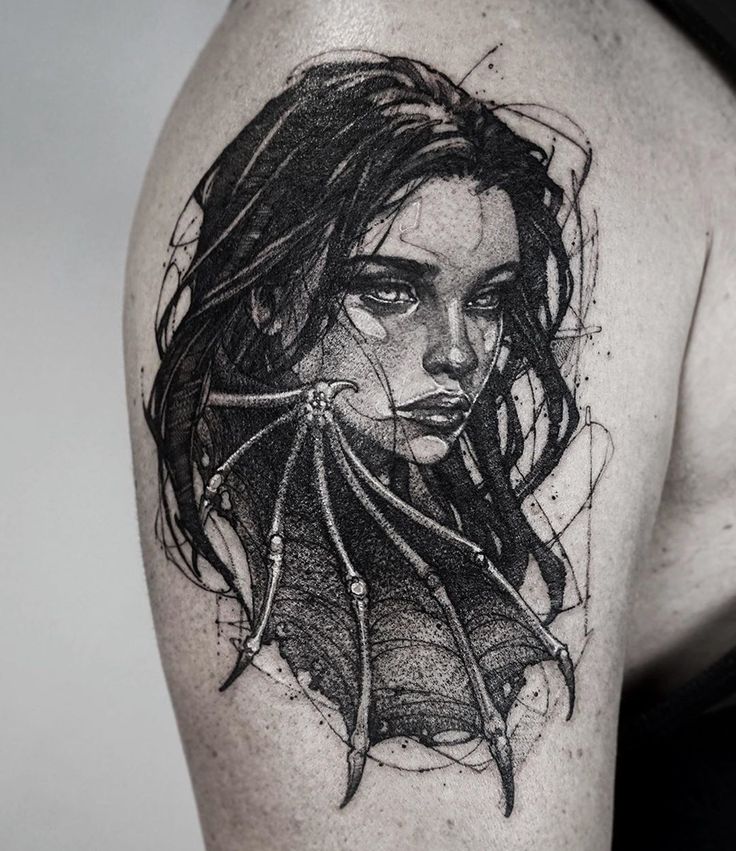 a woman's shoulder with an artistic tattoo design on the left side of her arm