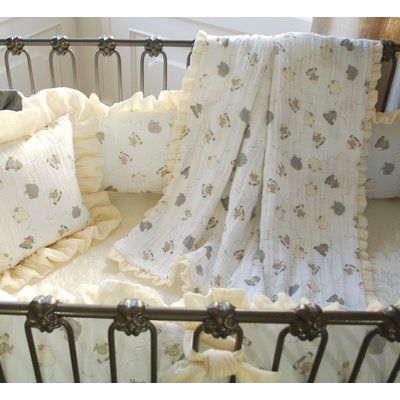 a baby crib with two pillows and a blanket on it's side, in front of a window