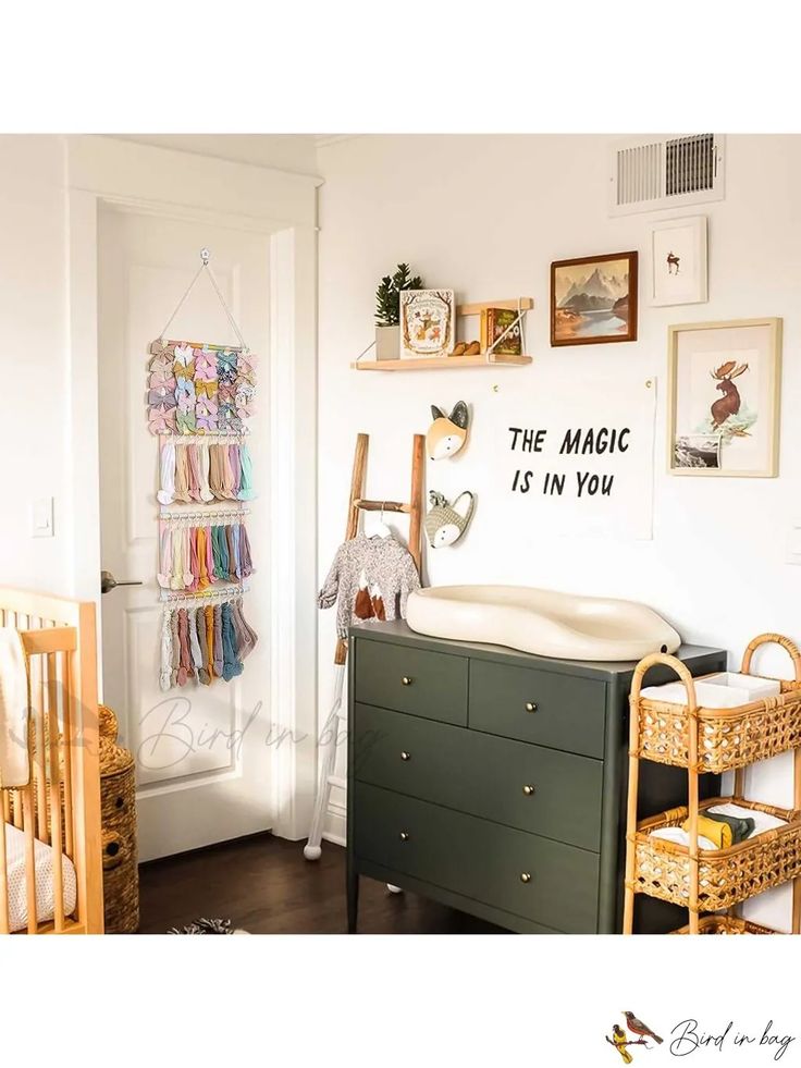 a baby's room with a crib, dresser and wall hanging on the wall