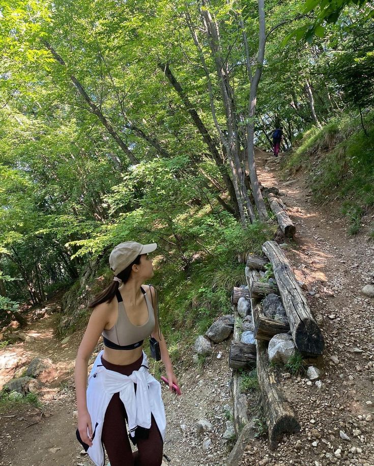 a woman walking down a trail in the woods