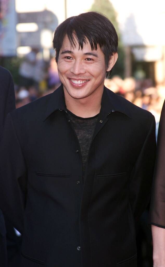 a young man smiles as he stands in front of a group of people on the red carpet