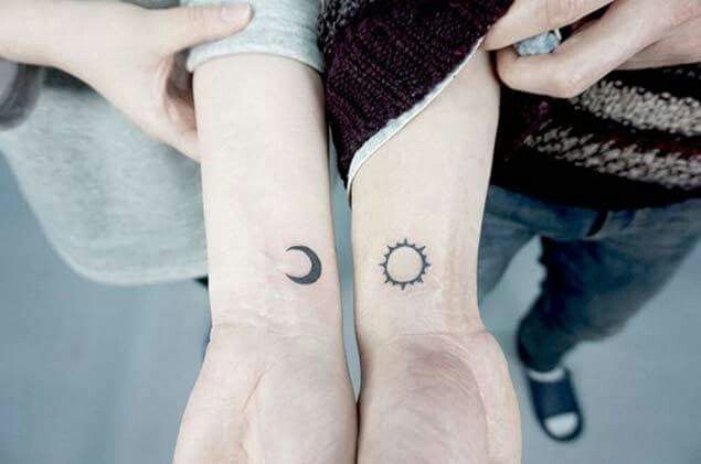 two people with matching tattoos on their arms, one has a sun and the other has a moon