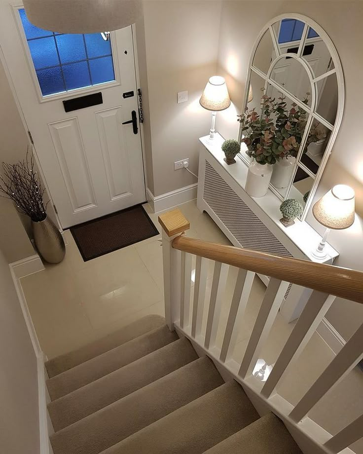 the stairs lead up to an entryway with a mirror and lamp on each side