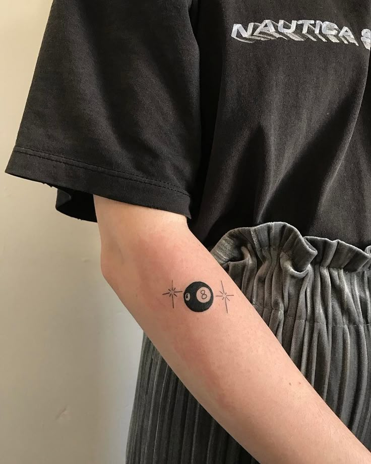 a person with a tattoo on their arm holding a black object in the other hand