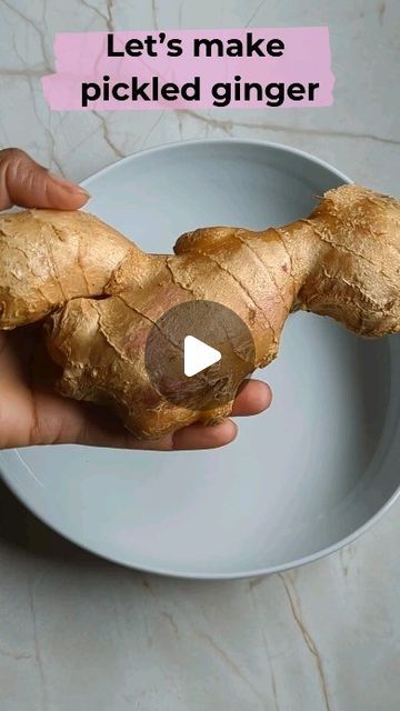 a person holding a piece of ginger on a plate with the caption let's make picked ginger