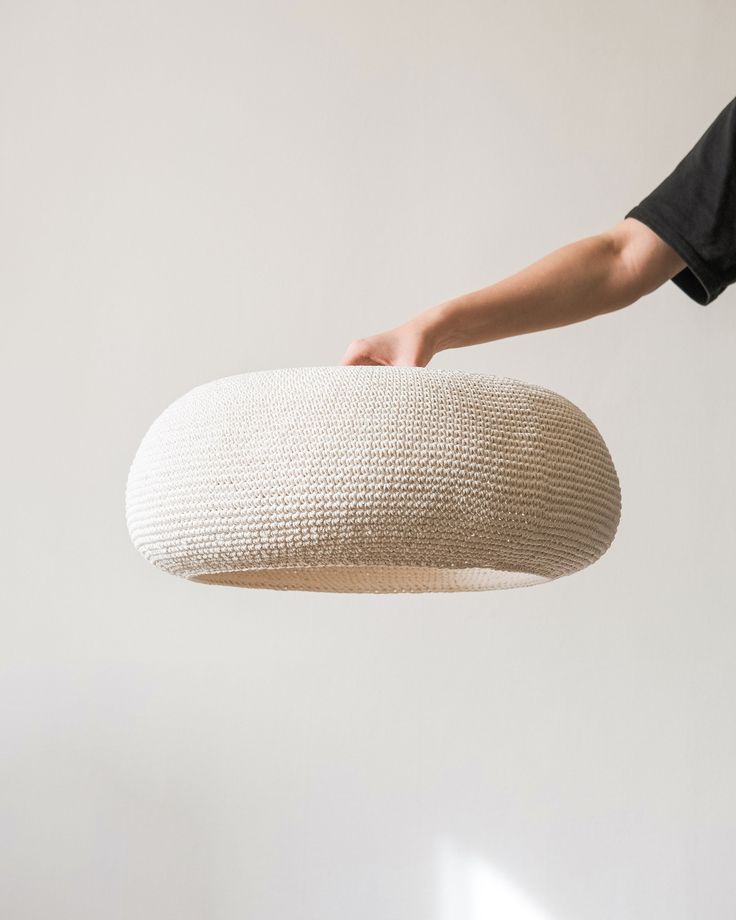 a person is holding a large white cushion in the air with their hand on it