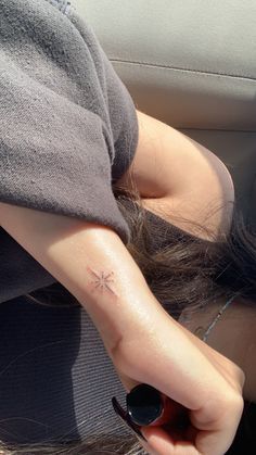 a woman with a small cross tattoo on her left arm in the back seat of a car