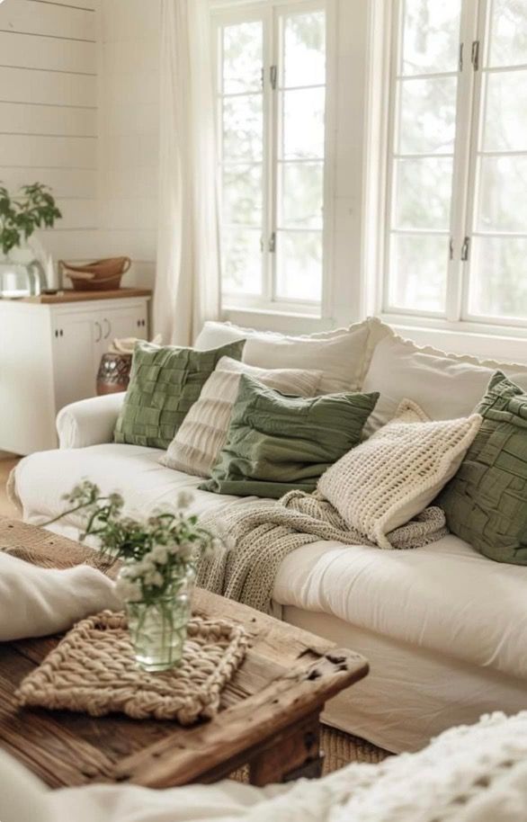 a living room filled with white furniture and lots of pillows on top of it's couch