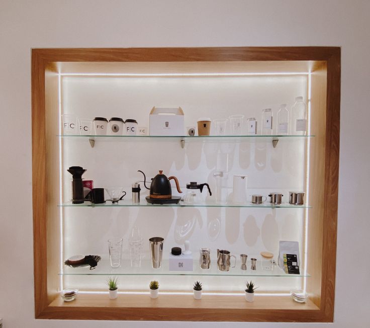 a display case filled with lots of different types of coffee pots and mugs on glass shelves