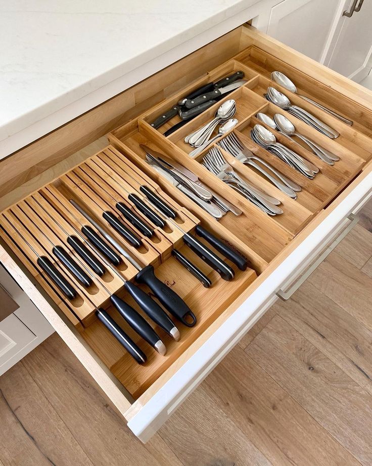 an open drawer with utensils and spoons in it