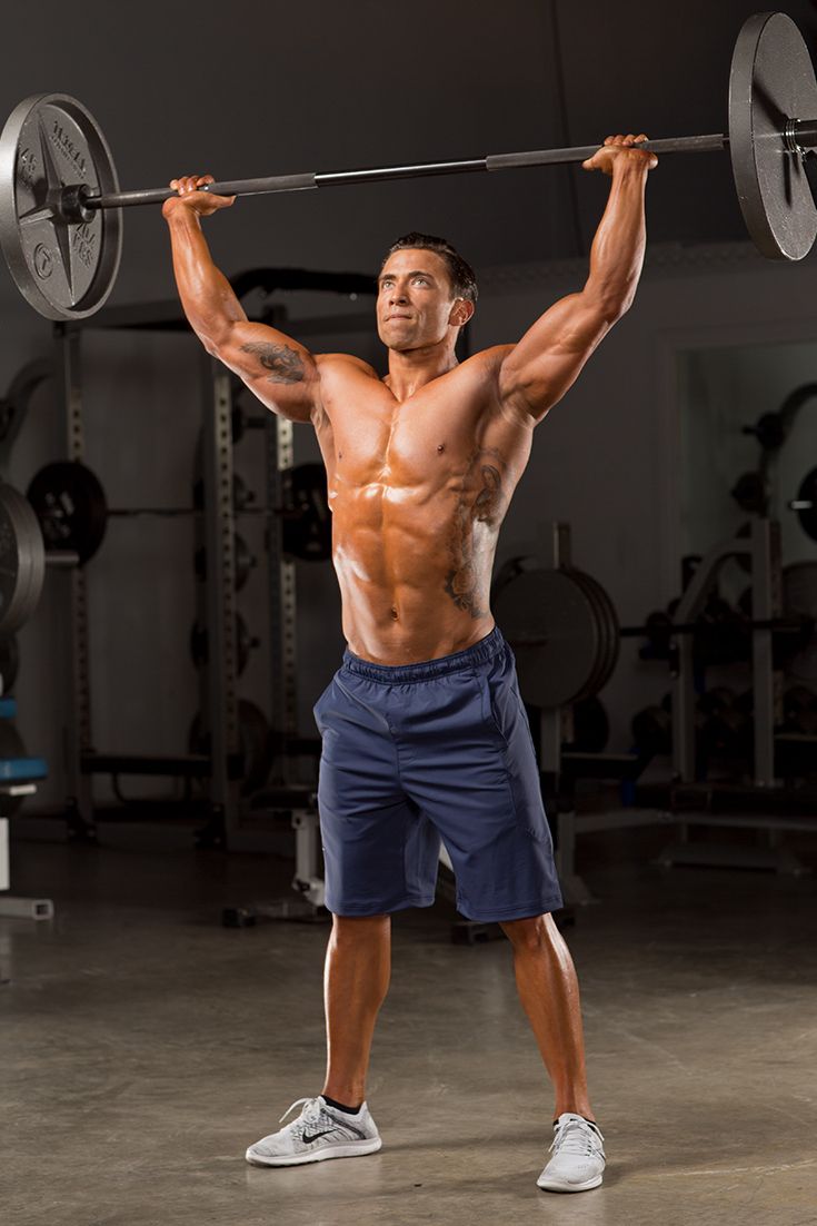 a shirtless man lifts a barbell in the gym