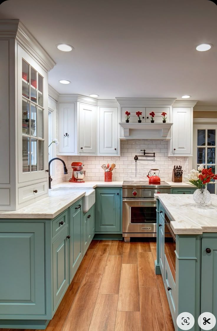 a kitchen with white and blue cabinets, wood flooring and an island in the middle