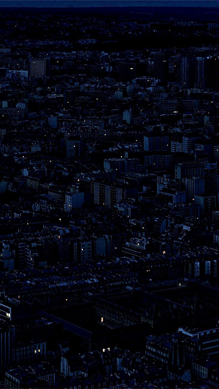 an aerial view of the city at night with buildings lit up and lights on in the foreground