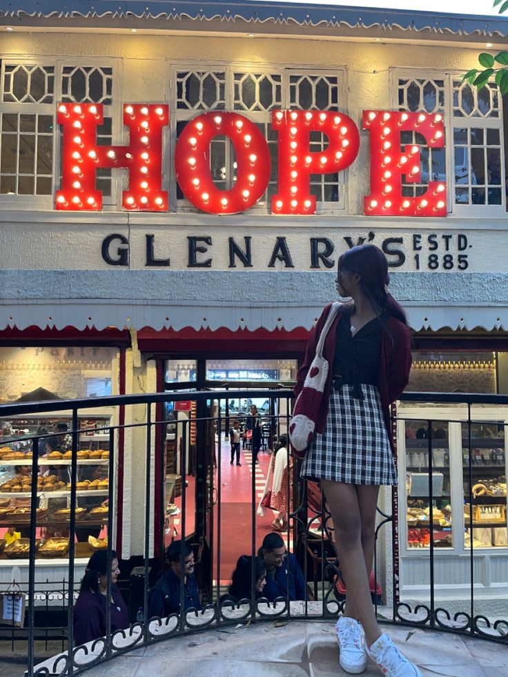 a woman standing in front of a store with the word hope on it's sign