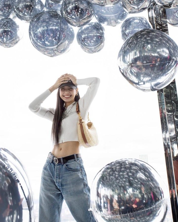 a woman is posing in front of some disco balls with her hands on her head