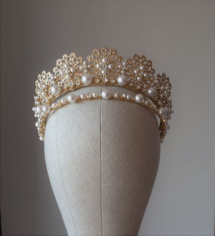 a gold tiara with pearls and beads on top of a mannequin headdress