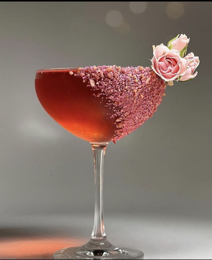 a wine glass filled with red liquid and pink sprinkles