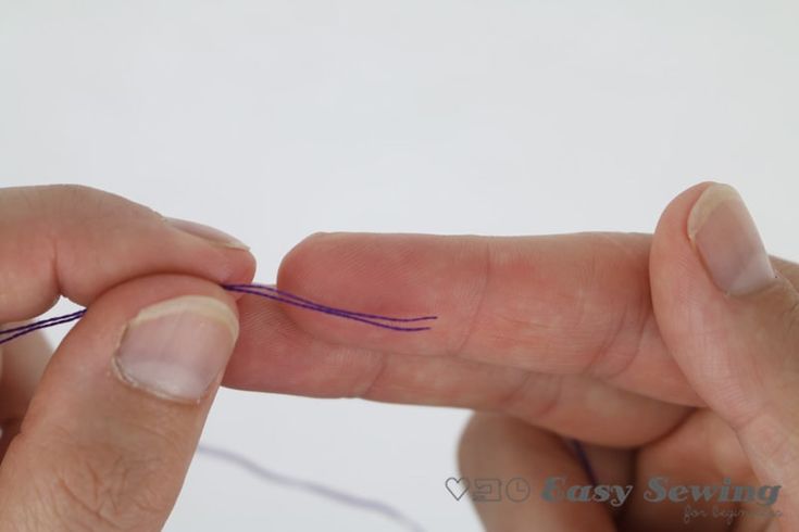 two hands are stitching together with purple thread on the end of their fingers and one hand is holding an object