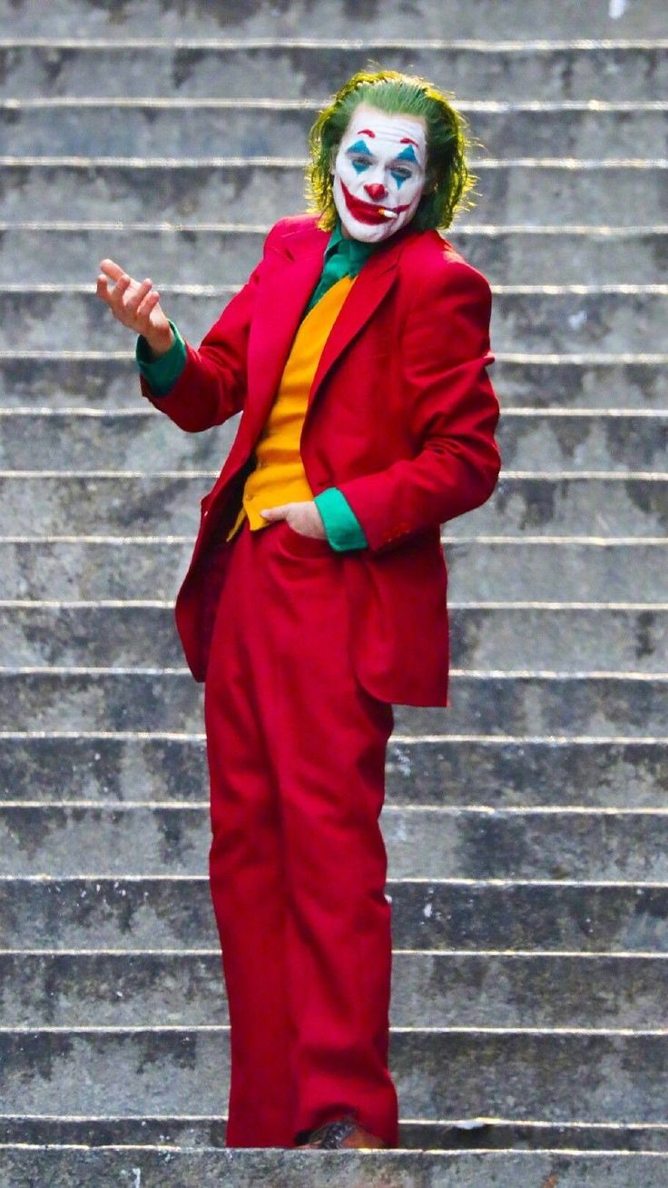 a man dressed as the joker standing in front of some steps with his hands out