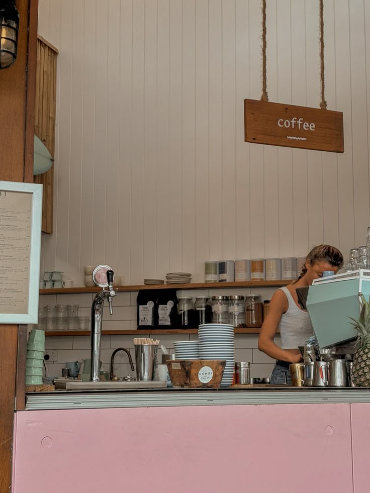 a woman standing behind a counter in a coffee shop