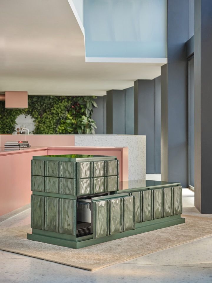 two green boxes sitting on the ground in front of some pink and grey walls with plants